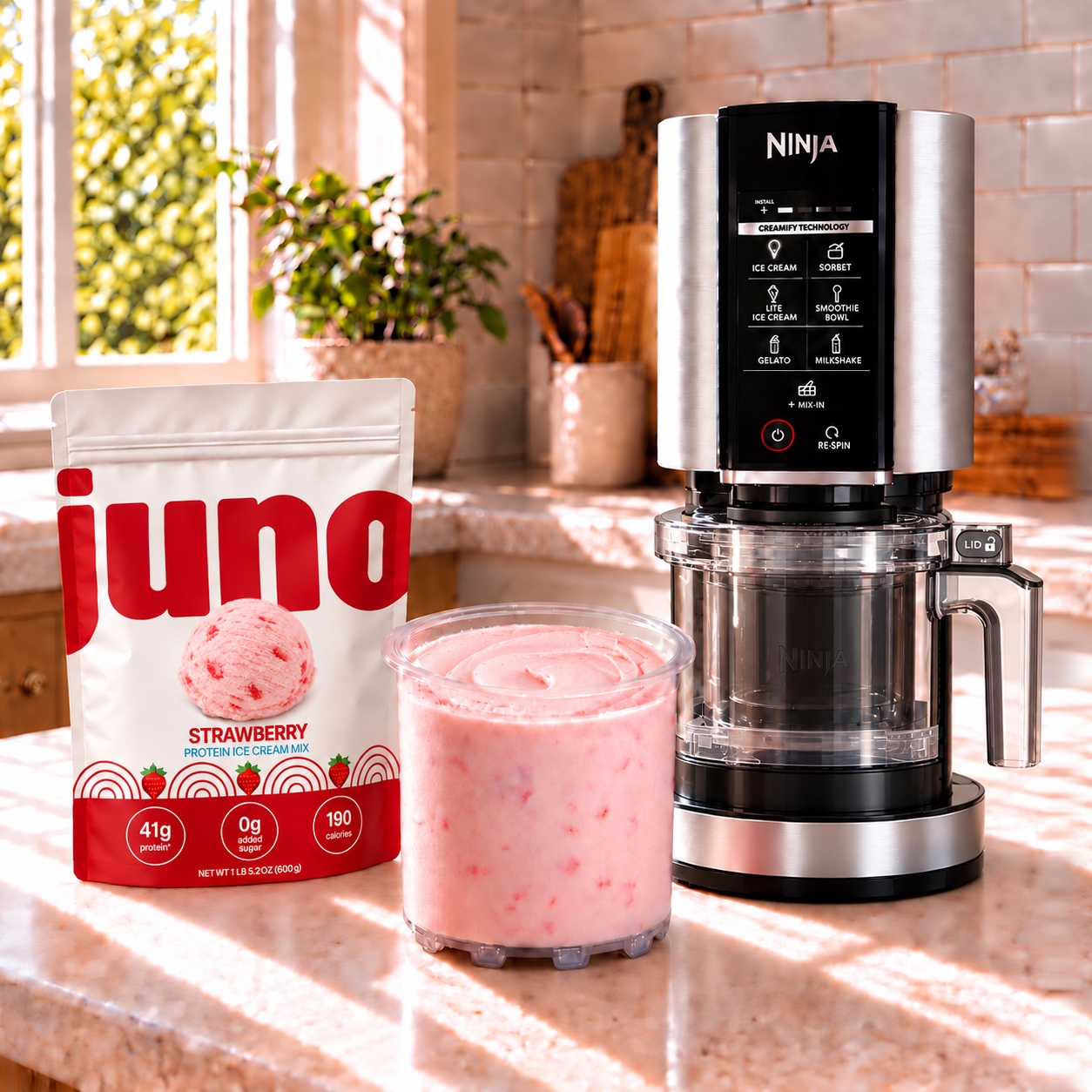 Juno Strawberry pouch beside a freshly spun strawberry pint and a Ninja CREAMi machine